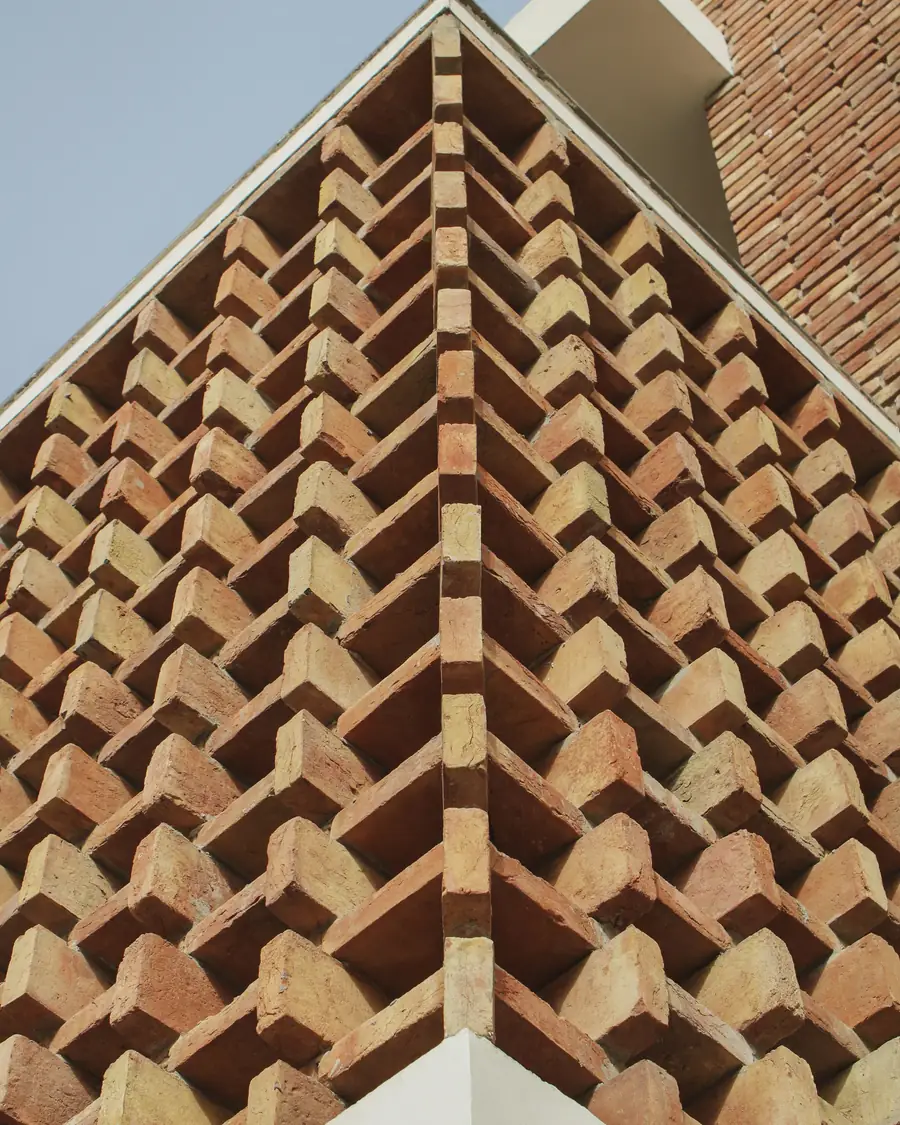 The corner of a red-brick façade laid in a zigzag pattern