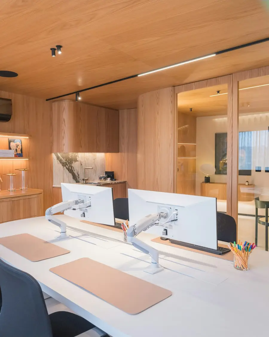 A workspace lined in pale timber with a curved white desk