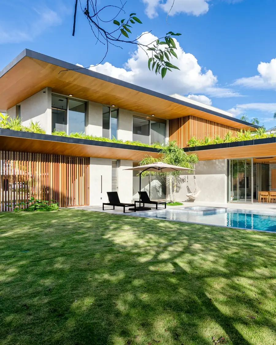 A tropical house with a wide flat roof, a pool and a lawn