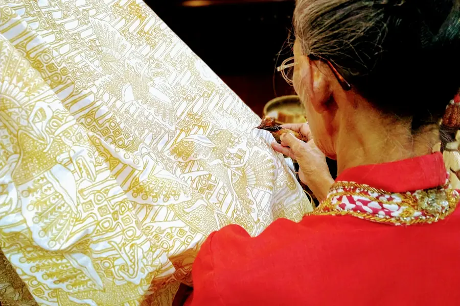 A batik artist painting wax onto cloth