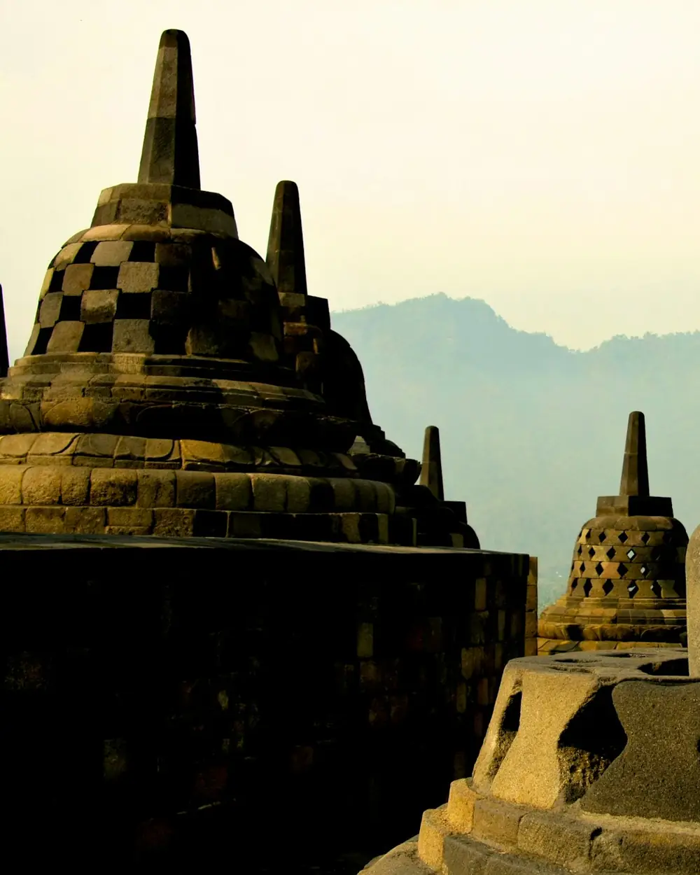 Stone stupas and a Buddha statue at Borobudur in golden light
