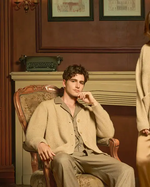 A man in a beige lounge set sitting in a leather chair