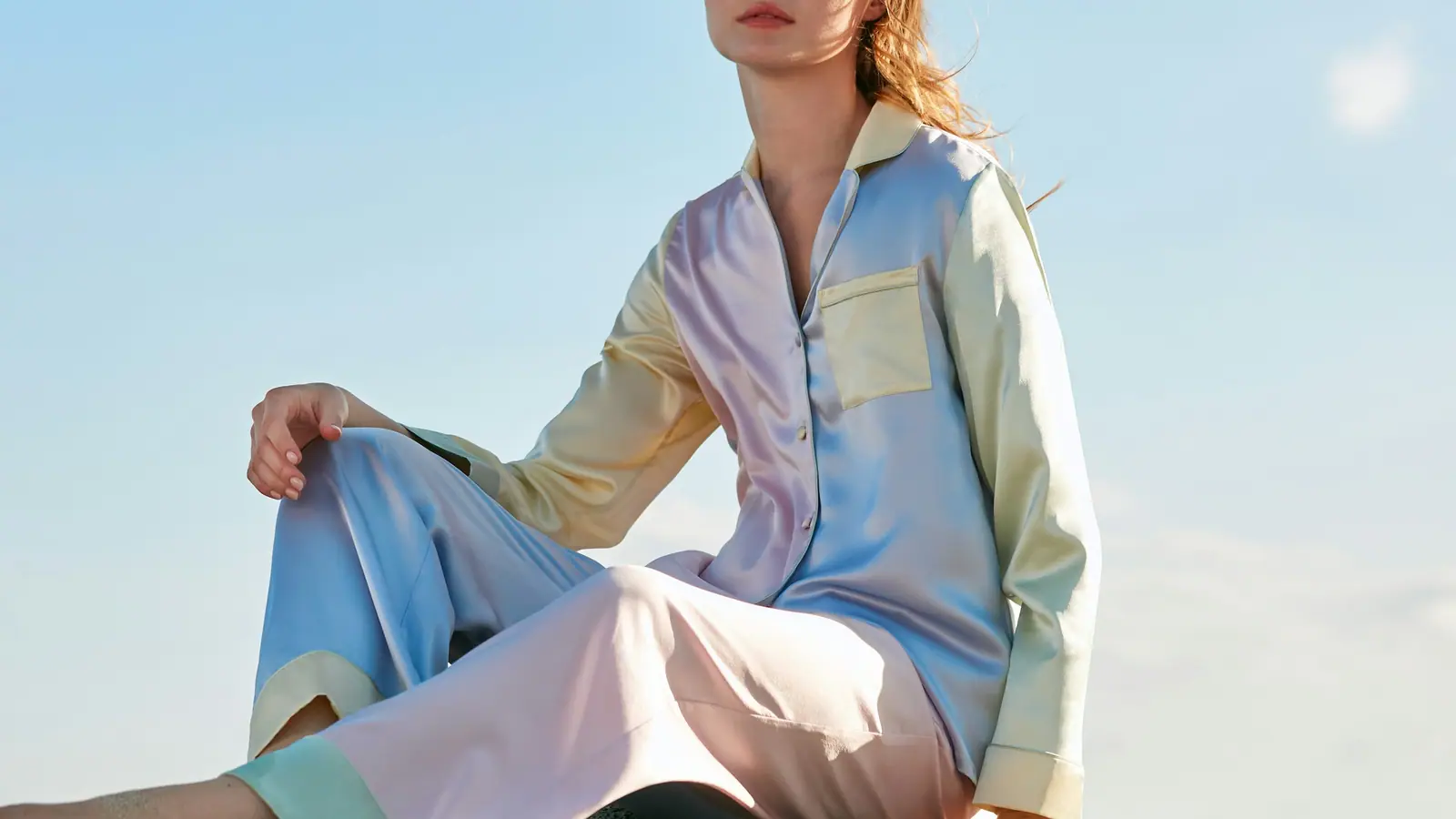 A woman in a pastel pyjama set sitting under a blue sky
