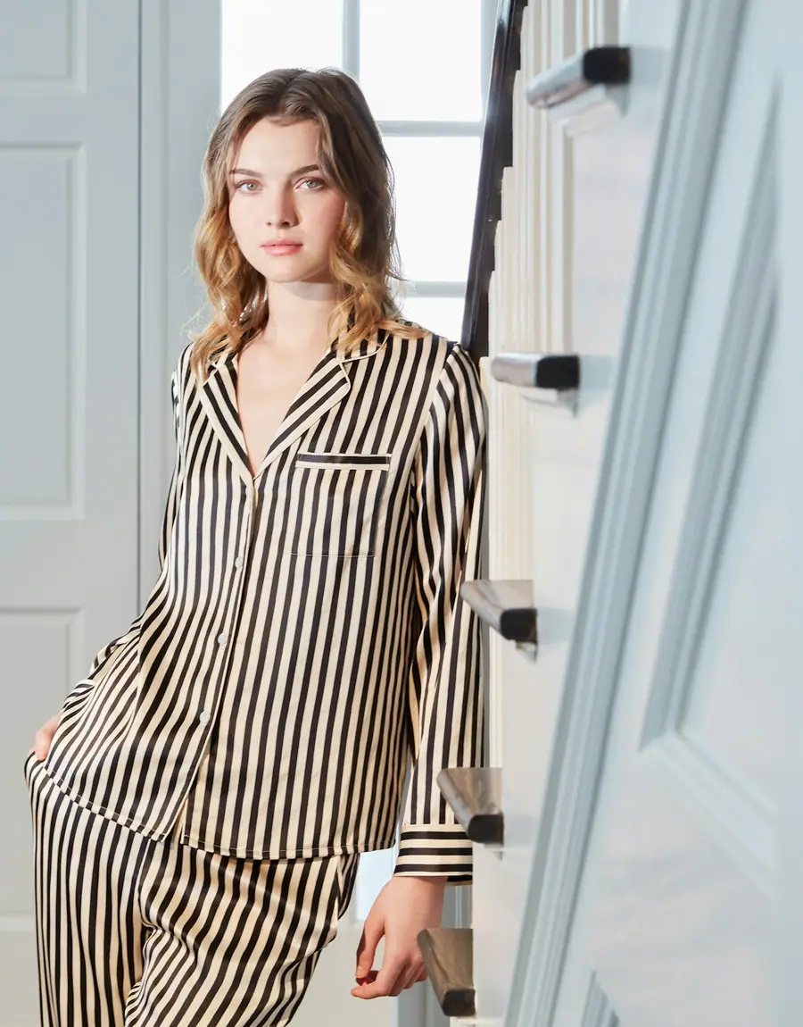 A woman in a striped pyjama set leaning in a doorway