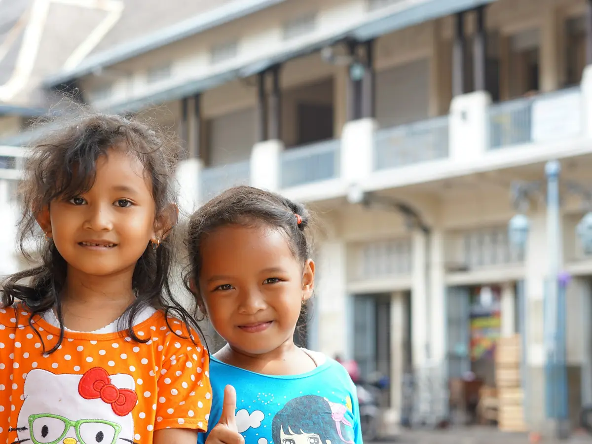 Two smiling young girls outside a school building